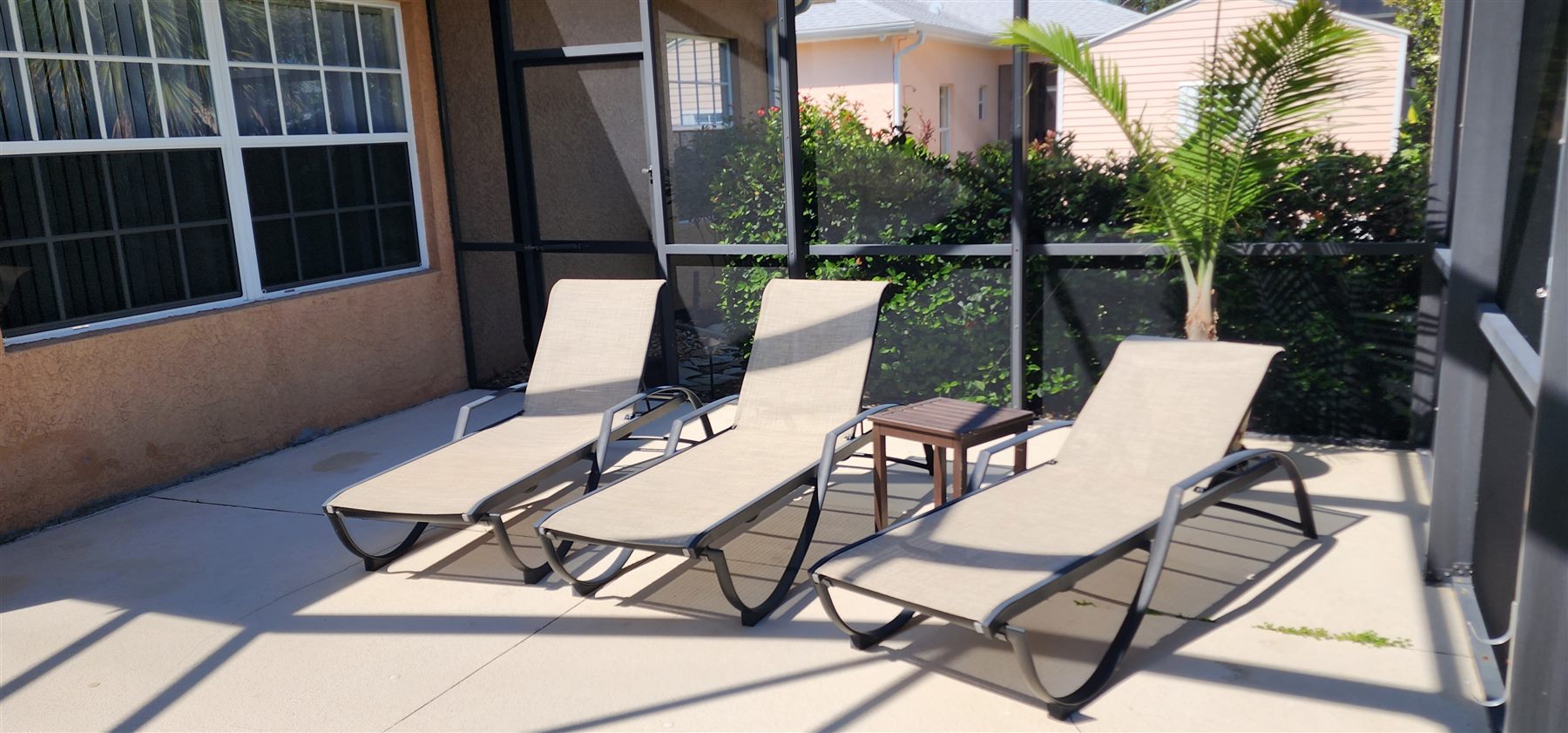 Poolside lounge chairs on the screened lanai